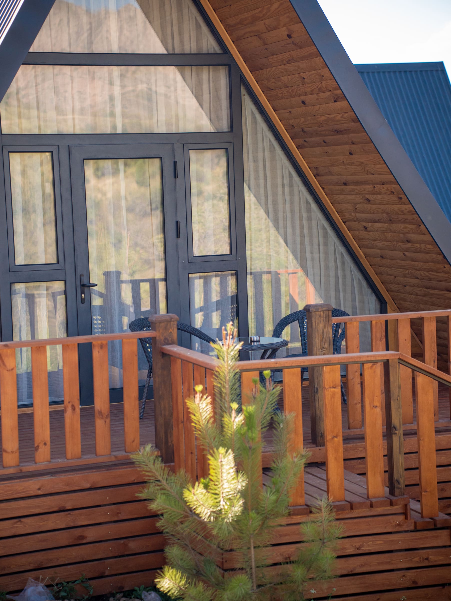 A-frame uychaning yog'och panjarali va panoramali eshikli terrasasi